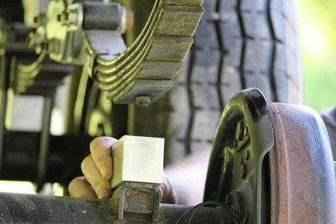 Trailer suspension inspection beside a wheel and leaf spring